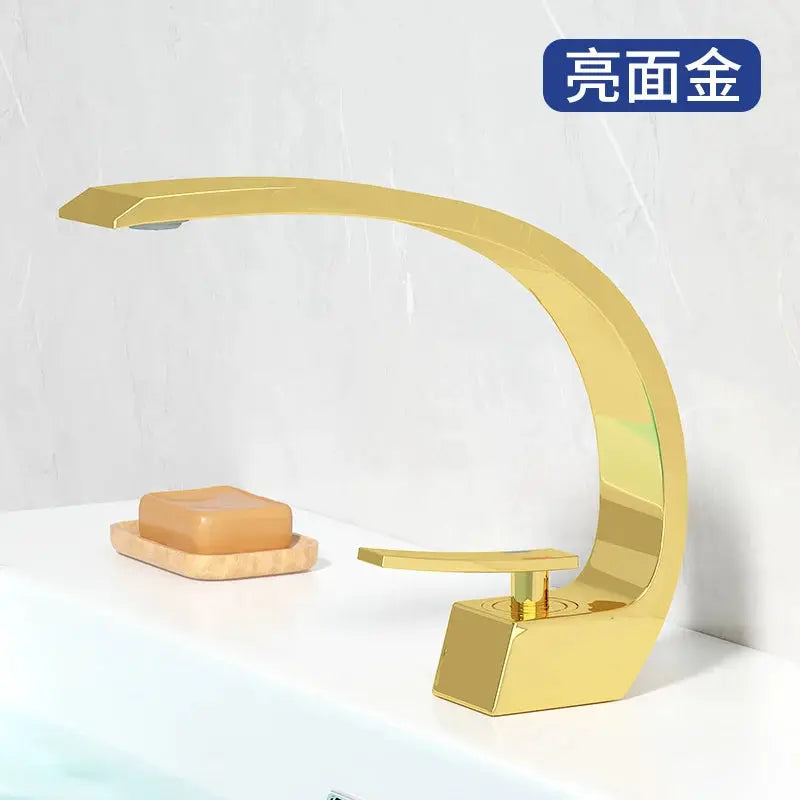 Basin faucet with gold finish, modern curved design, single-handle hot/cold mixer