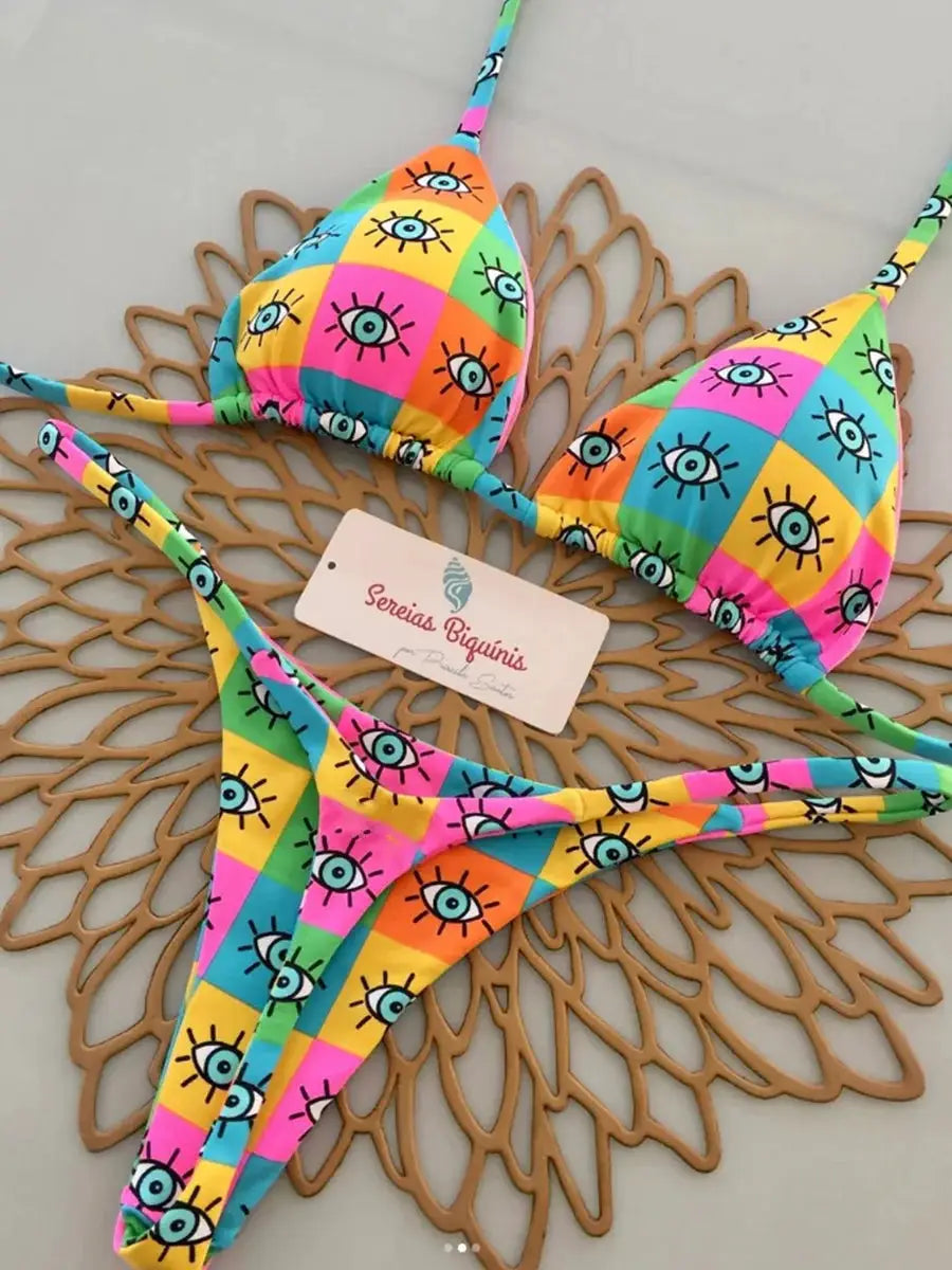 Two-piece halter bikini set in bright rainbow patchwork with eye motifs; Sereias Biquinis branding.
