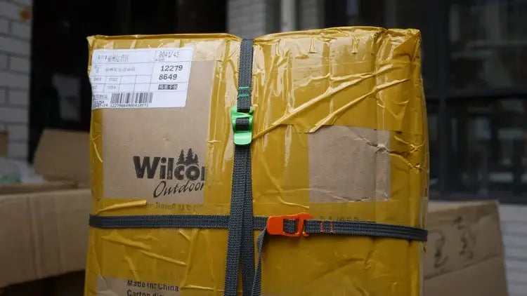 Two black luggage straps with green quick-release buckle and orange release buckle securing a yellow Wilco Outdoor box