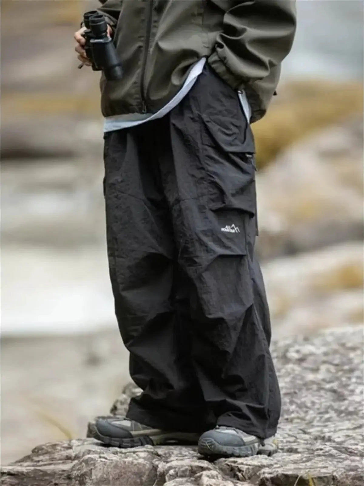 Men's black cargo mountaineering pants with multiple pockets and Simples Market logo on pocket