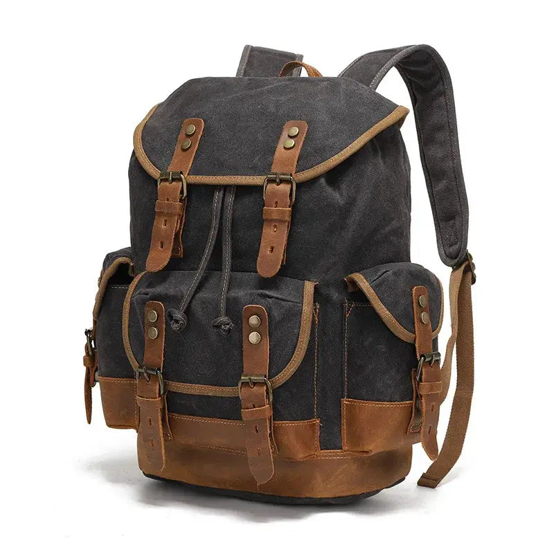 Vintage canvas backpack by Simples Market; dark waxed fabric with brown leather straps and multiple front pockets.