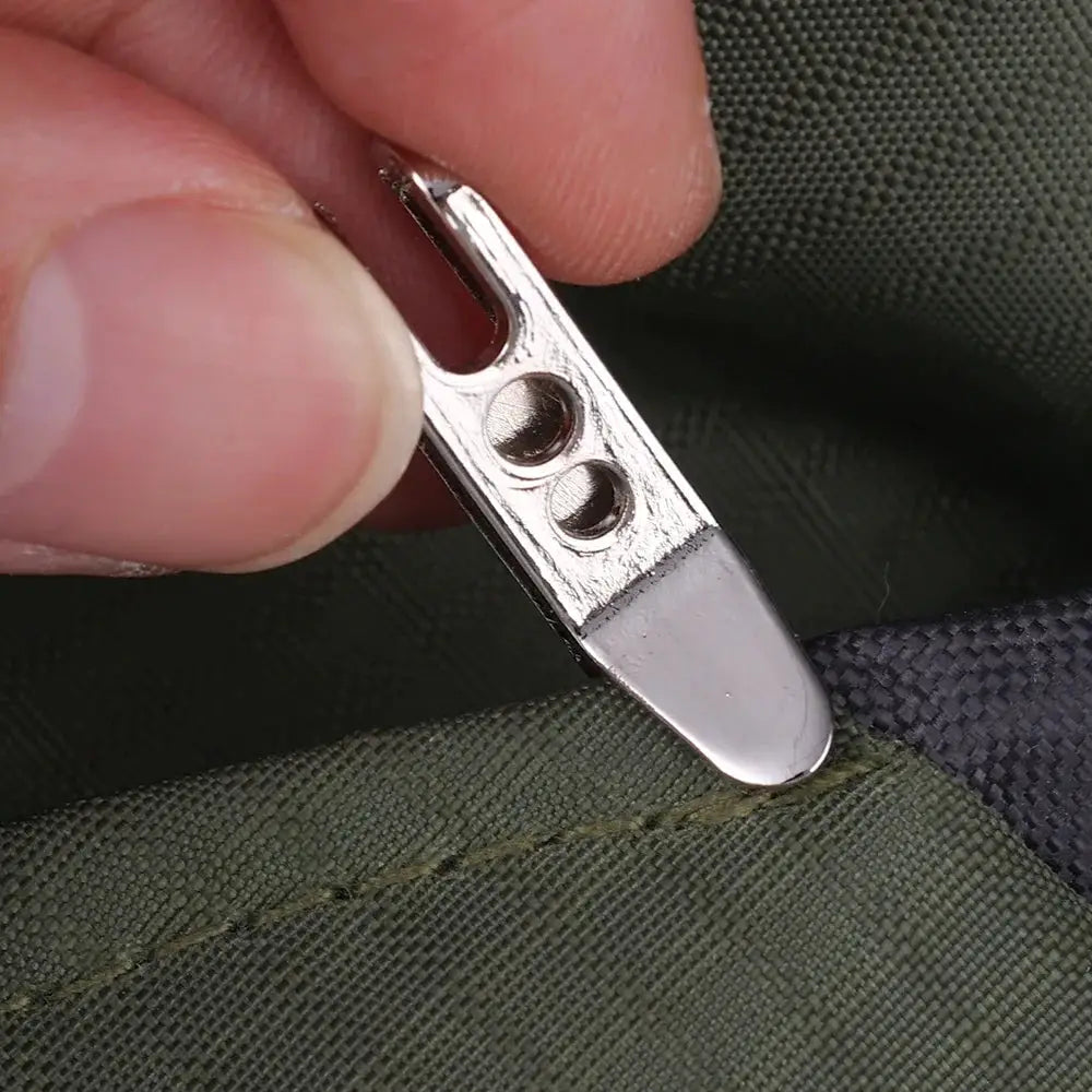 Silver metal EDC pocket suspension clip with key carabiner, shown on green fabric.