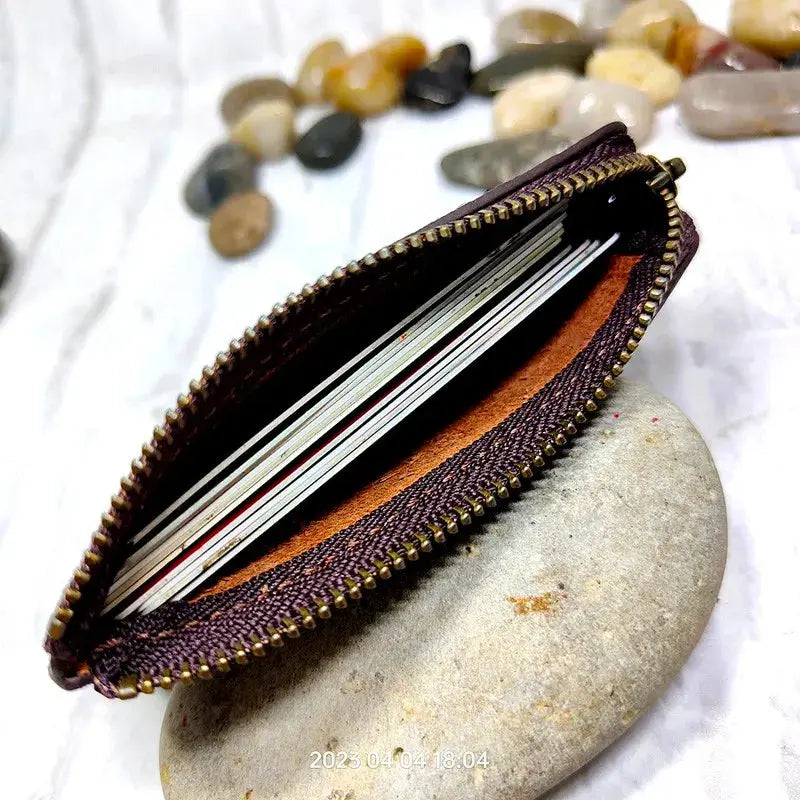 Mini leather zipper waist bag with card slots; burgundy exterior and brass zipper