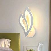 Leaf-shaped LED wall lamp with white frame and warm ambient light for modern bedroom decor.