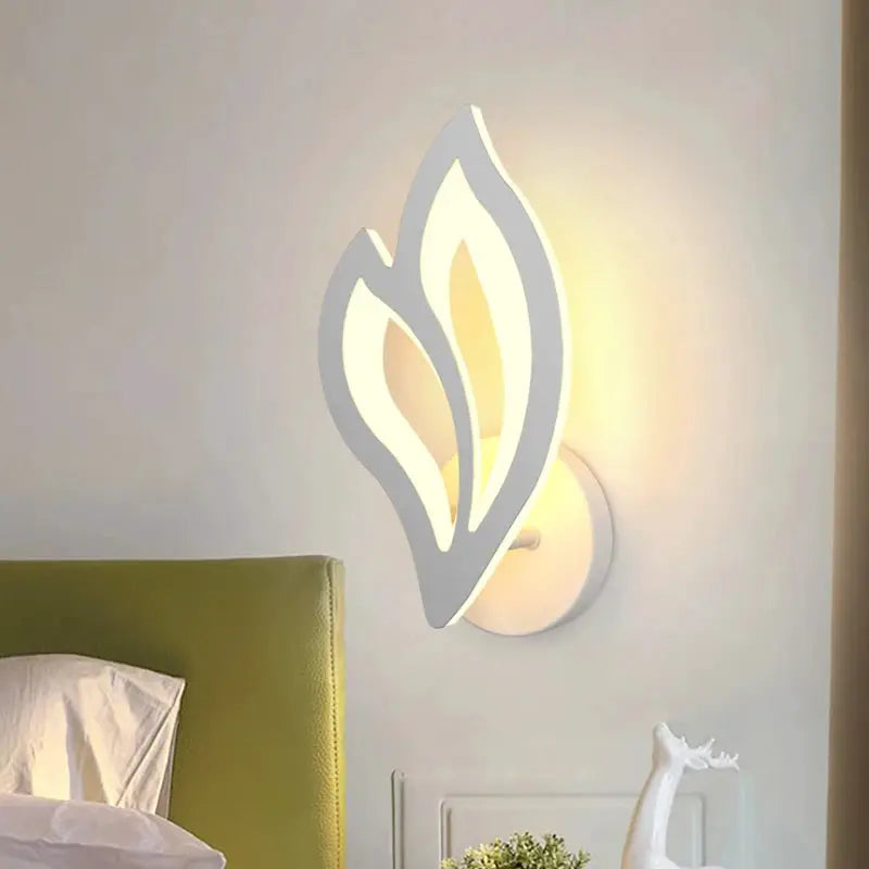 Leaf-shaped LED wall lamp with white frame and warm ambient light for modern bedroom decor.