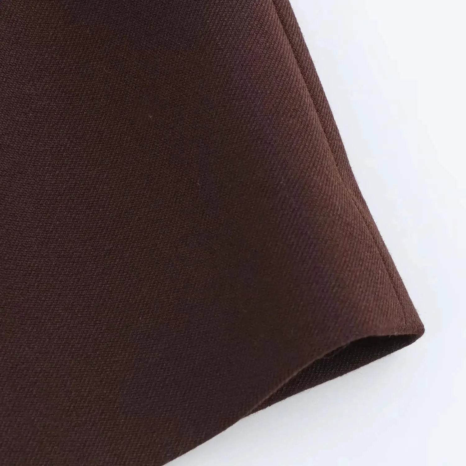Brown textured blazer fabric close-up, showing tight weave and folded edge, Simples Market