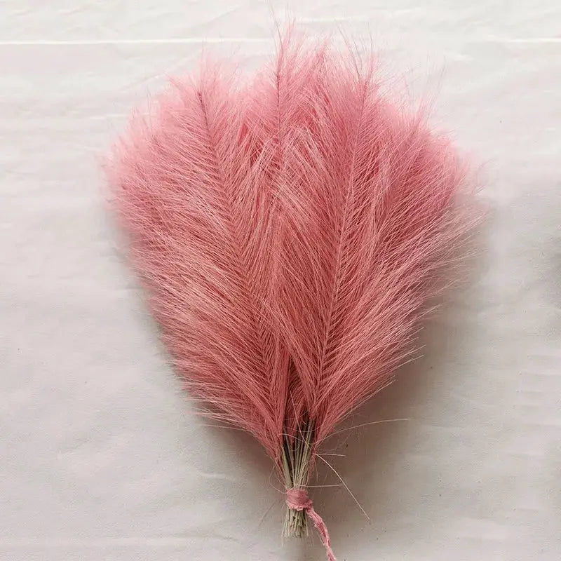 Artificial pink pampas grass bouquet for boho decor; fluffy reed stems bundled.