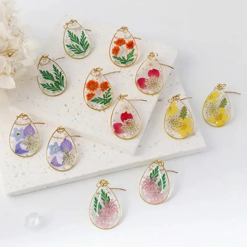 Teardrop epoxy resin earrings with colorful pressed flowers in a gold-tone bezel