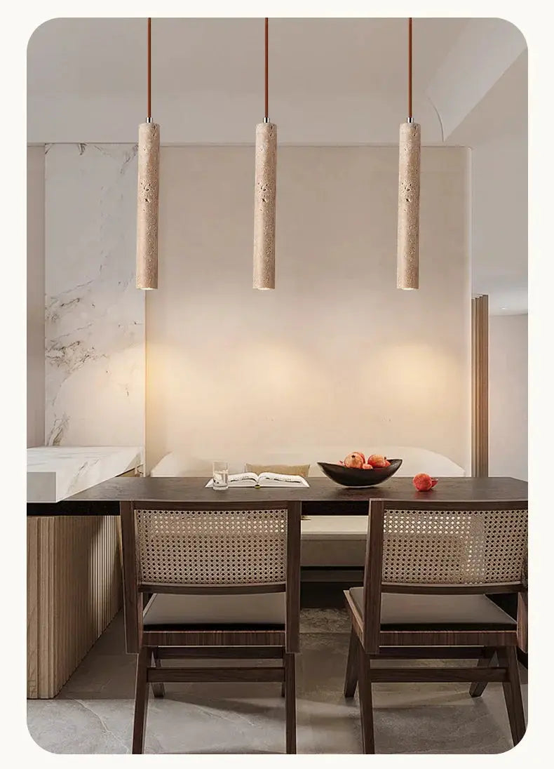 LED pendant lamp trio: three long cylindrical beige textured lights over a dining table with cane-back chairs.