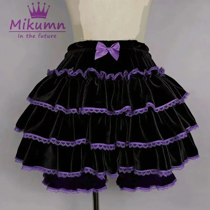 Black velvet lantern shorts with tiered ruffles, purple lace trim and a purple bow at the waist; Mikumm logo visible