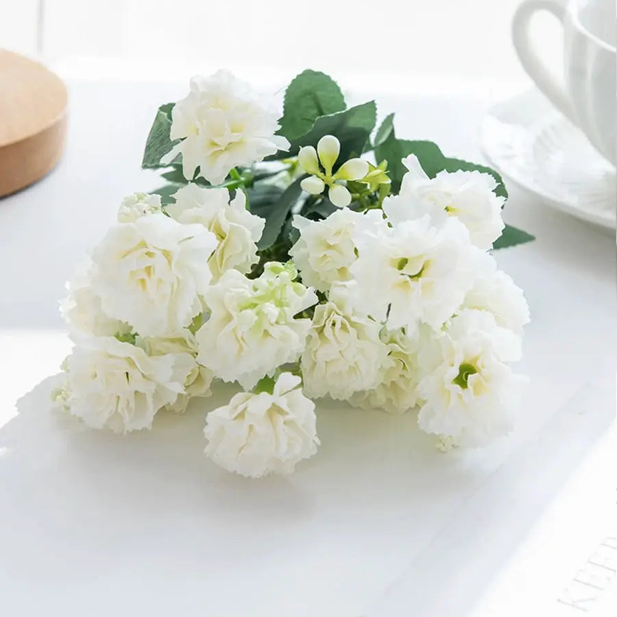 White artificial carnations bouquet with green leaves and soft petals.