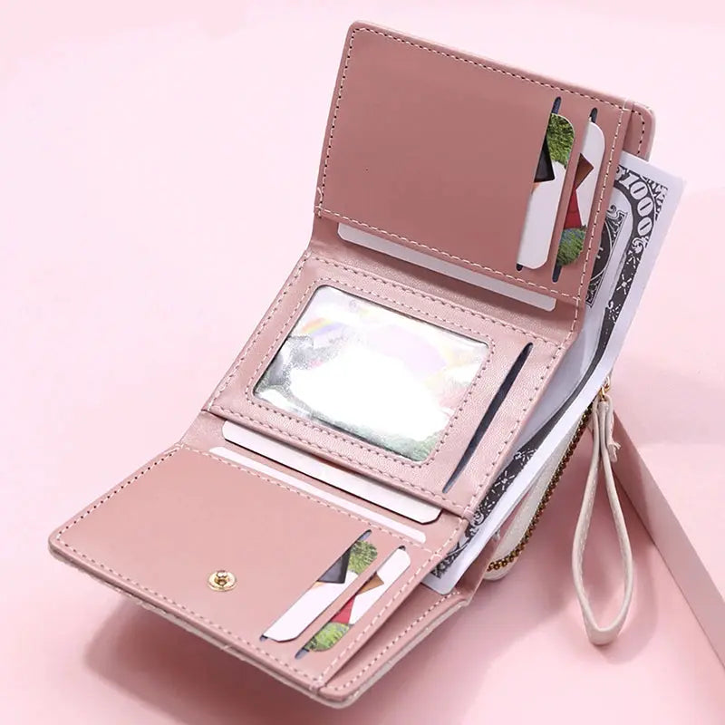 Simples Market women's pink PU leather tri-fold wallet with card slots, ID window, cash pockets, and a wrist strap.