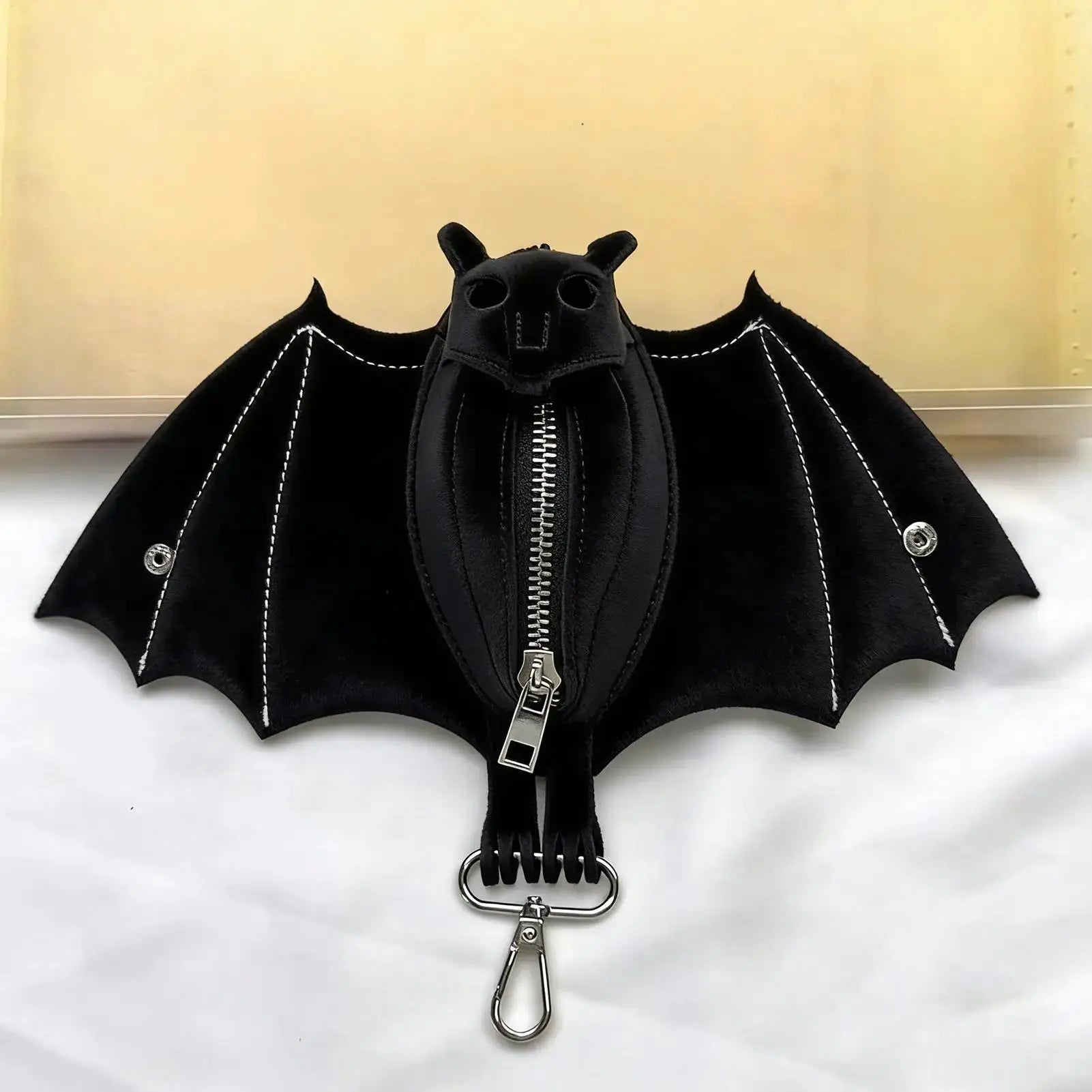Bat-shaped coin purse keychain in black PU leather with foldable wings and silver hardware.