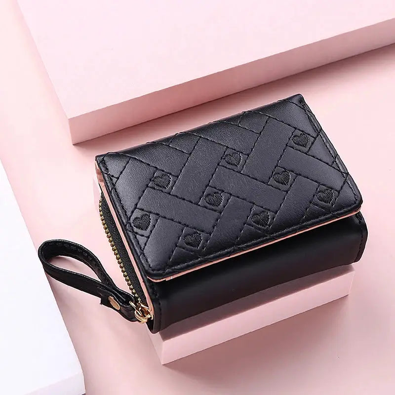 Women's wallet in black PU leather with pink edging and love-pattern design; zip-around with wrist strap.