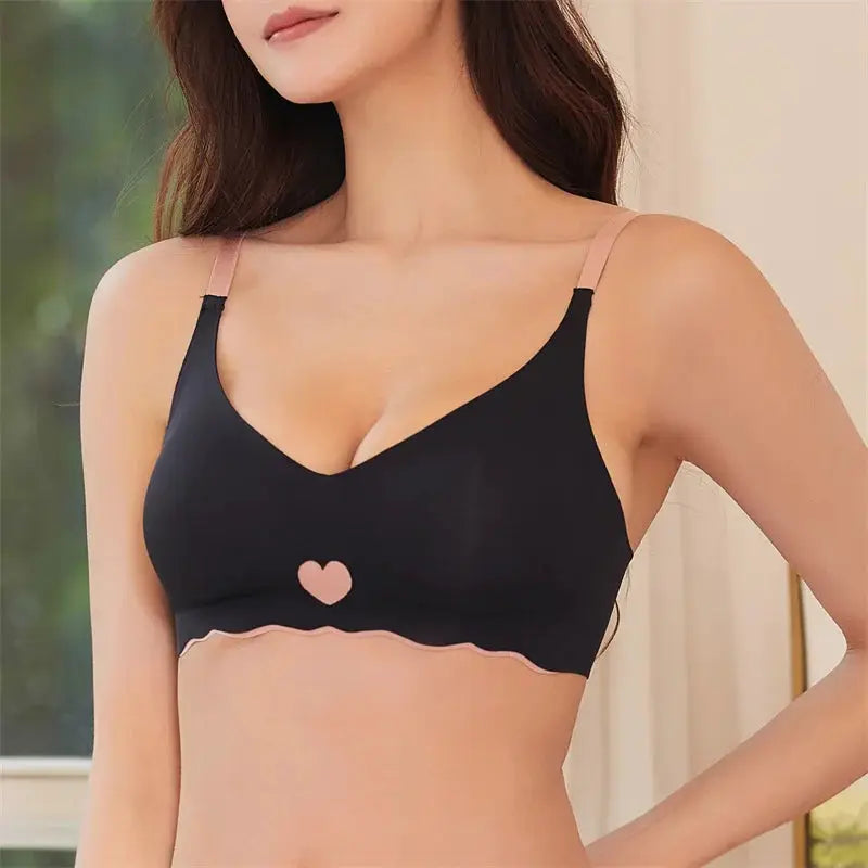 Women seamless bra with black cups, pink adjustable straps, pink heart center emblem, and scalloped pink bottom band.
