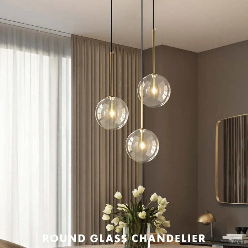 Pendant lights, round glass globes with gold suspension rods, set of three in a modern living room