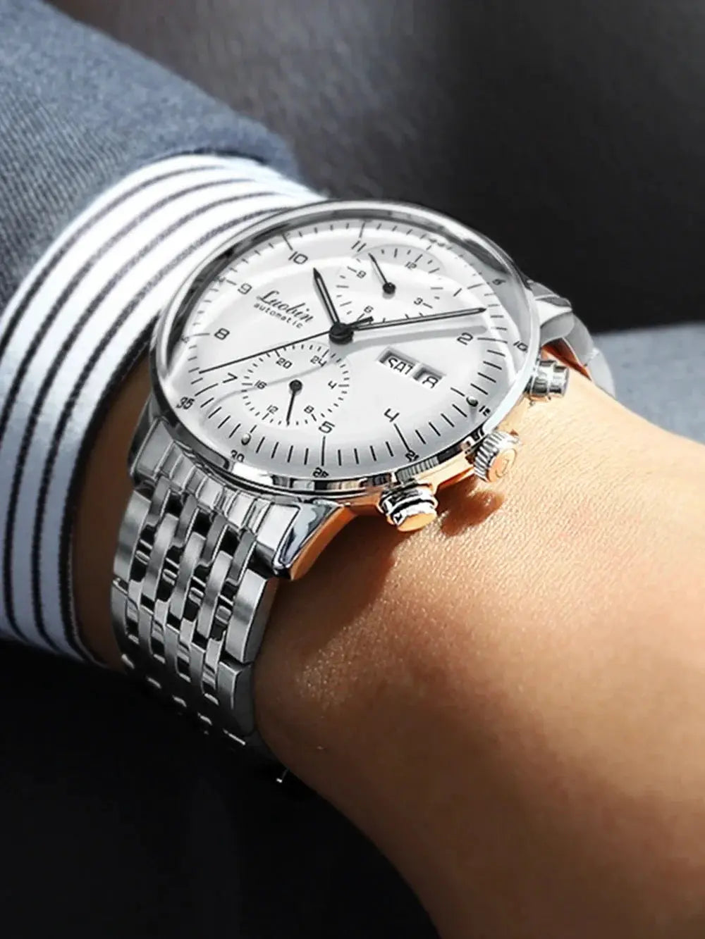 Men's stainless steel automatic wristwatch with white dial, chronograph subdials, date display, and silver bracelet.