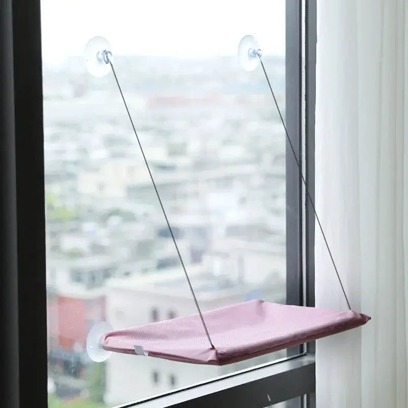 Pink cat hammock bed by Simples Market hanging from window with suction cups for a sunny window seat