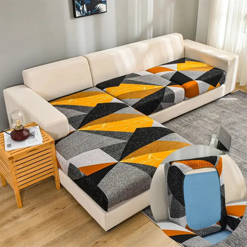 Geometric print corner sofa cover with elastic slipcover in orange, gray, black on a beige sectional.