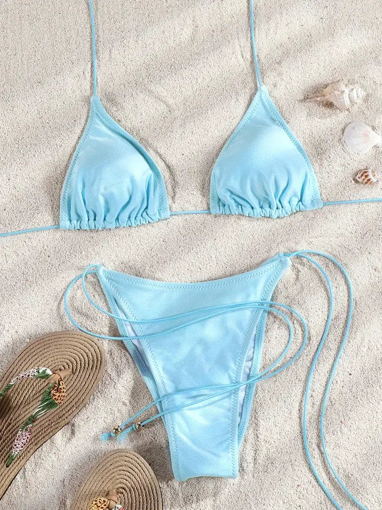 Blue string bikini set by Simples Market, triangle top and high-cut bottoms on sand