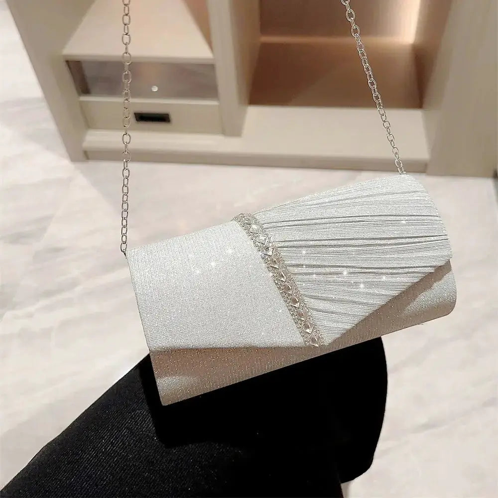 Sequined silver evening clutch with chain strap and pleated detailing.