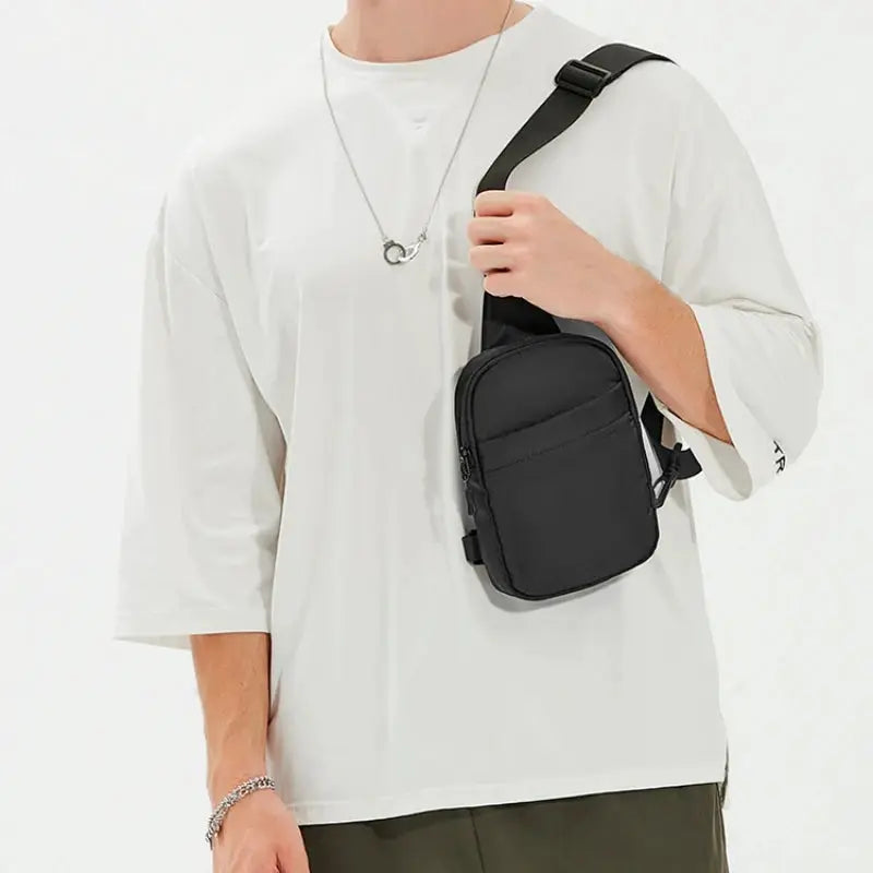 2-in-1 waist bag chest bag in black, worn crossbody by man in white top for outdoor travel