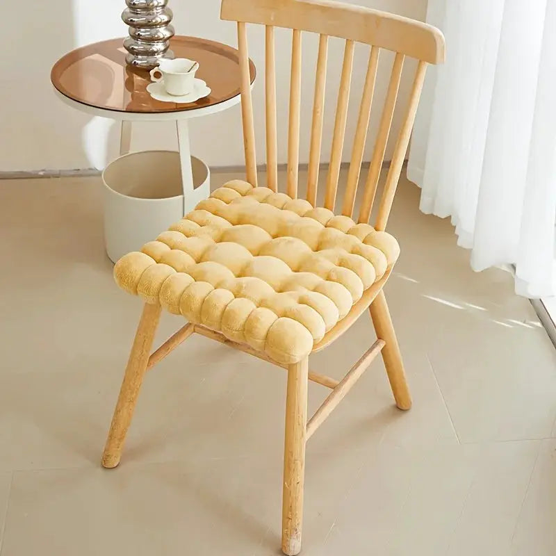 Large biscuit-shaped plush chair cushion in beige, tufted fabric on a wooden chair.