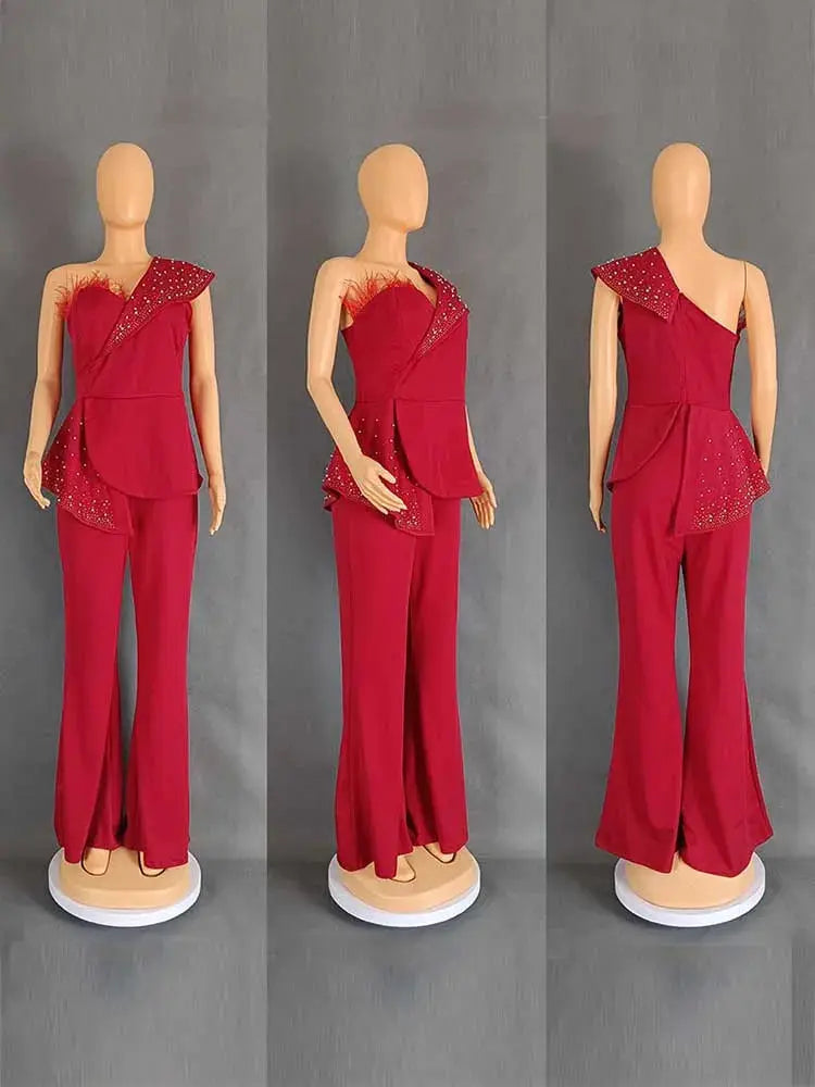 Red high-waist strapless jumpsuit with rivet-detailed asymmetrical peplum overlay.