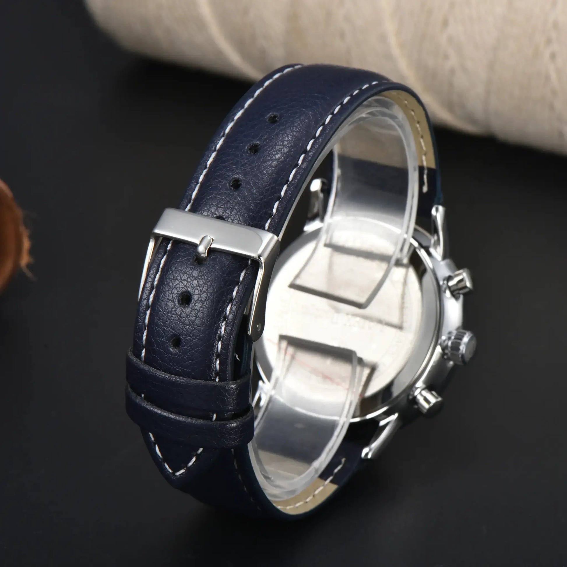 Watch with blue leather strap, white stitching, and stainless steel buckle