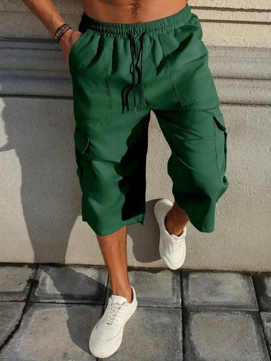 Green cargo shorts with drawstring waistband and multiple pockets, baggy capri length.