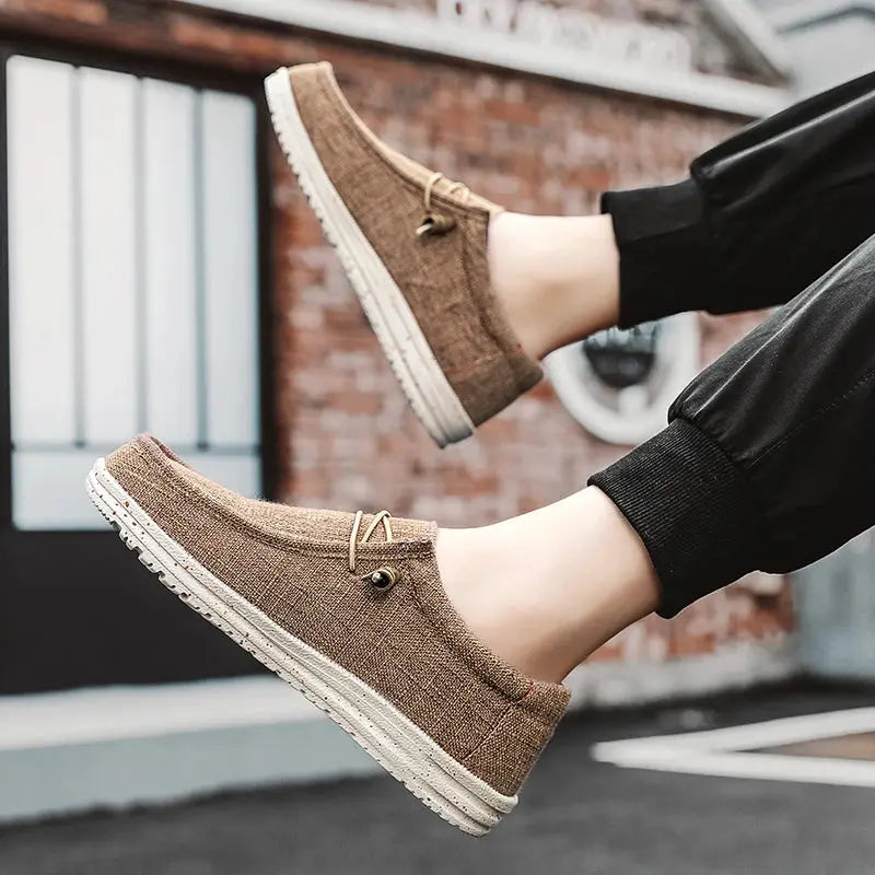 Pair of tan canvas loafers for men with white vulcanized sole, casual breathable footwear.