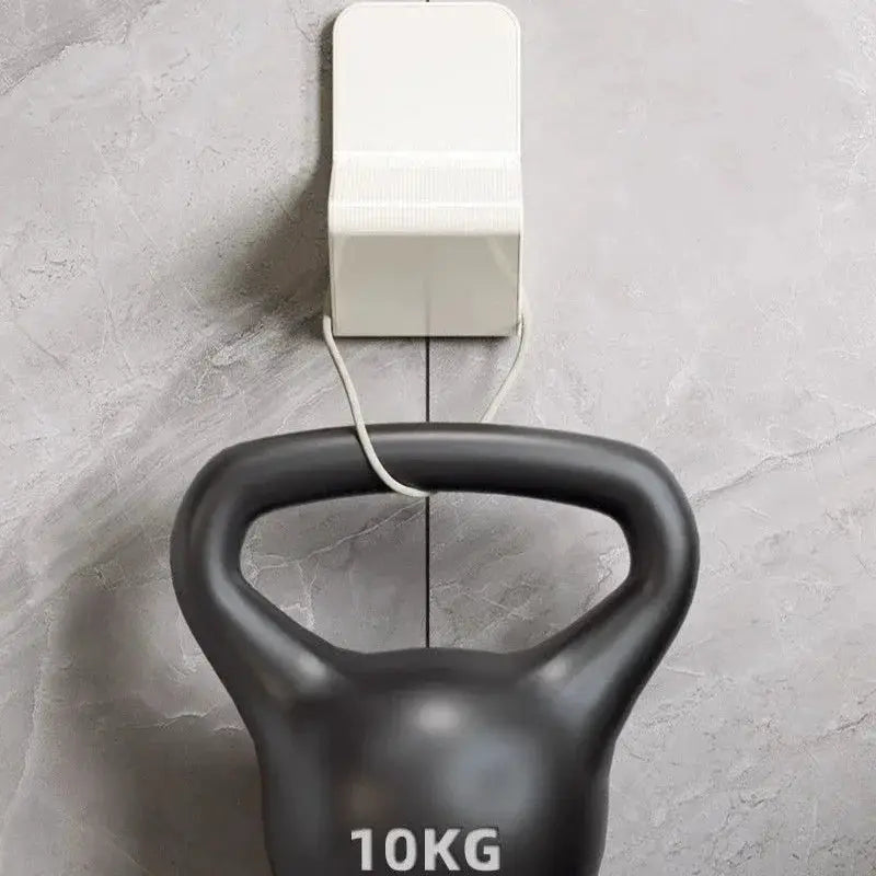 Kettlebell, black 10kg, in front of a white wall-mounted device on a gray tiled wall.