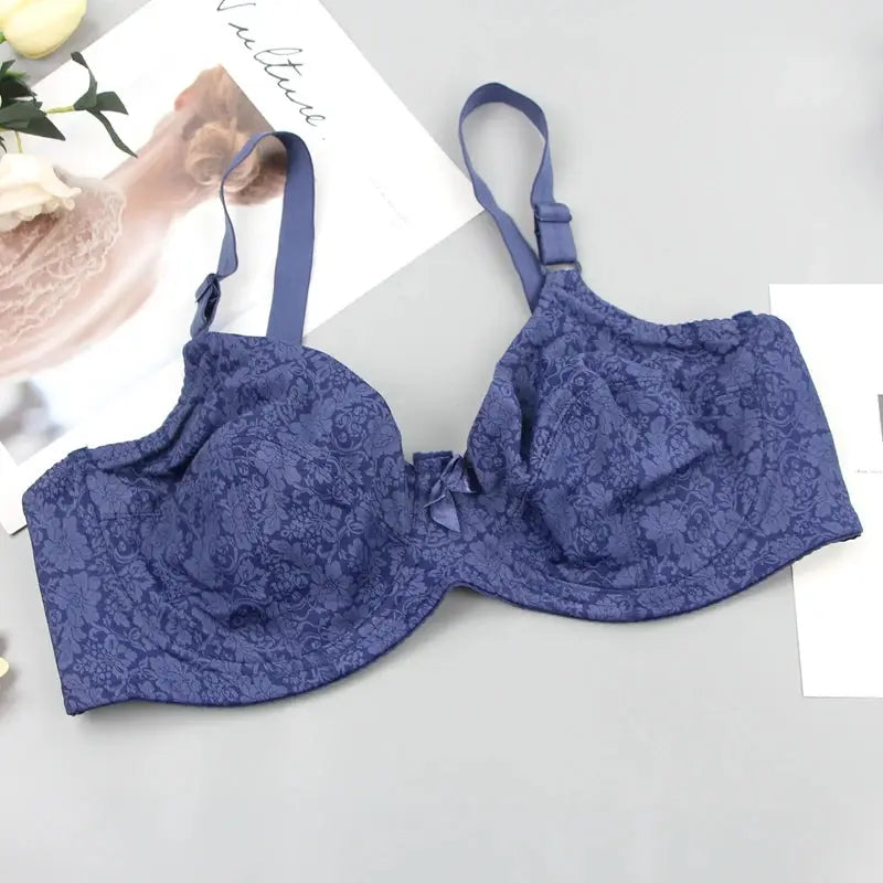 Bra in purple lace with floral pattern, bow center, and adjustable straps.