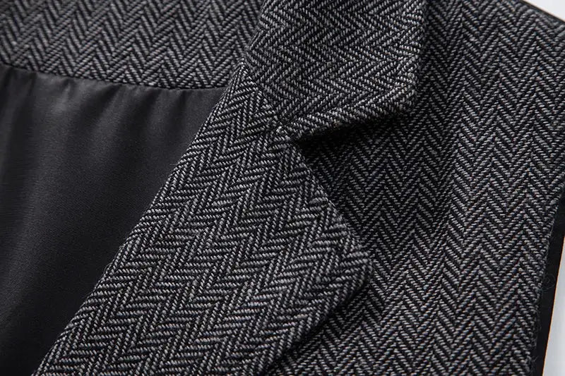 Men's tweed suit vest with dark gray herringbone pattern and lapel, close-up fabric