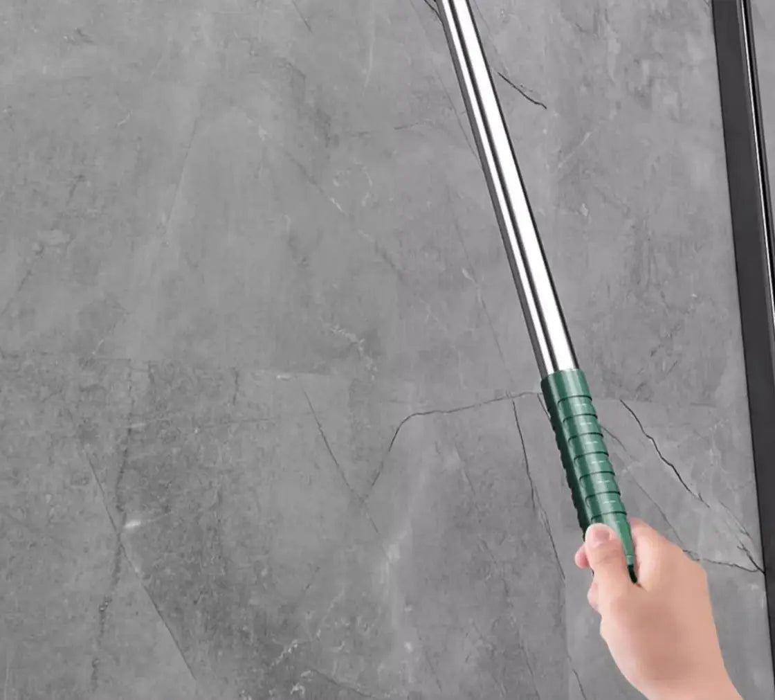 Simples Market silicone scraper broom with green grip, stainless steel handle, held over gray tiled floor