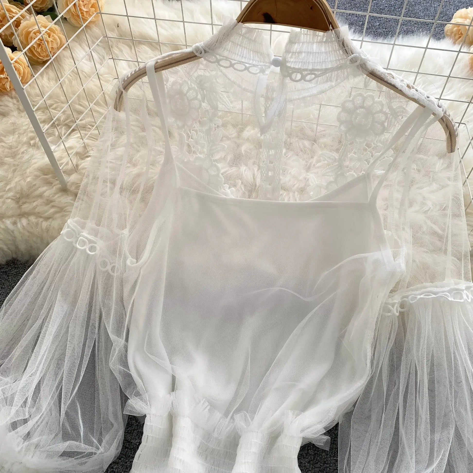 White lace puff-sleeve blouse on a hanger; sheer floral lace with high neck.