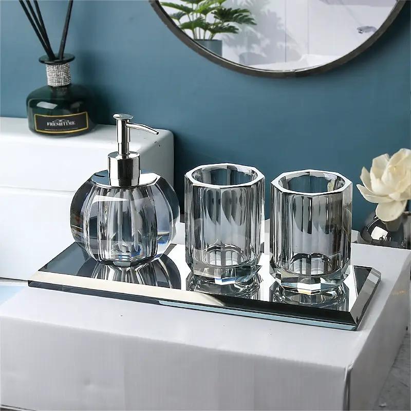 Glass lotion bottle with pump and two clear crystal cups on a mirrored bathroom tray