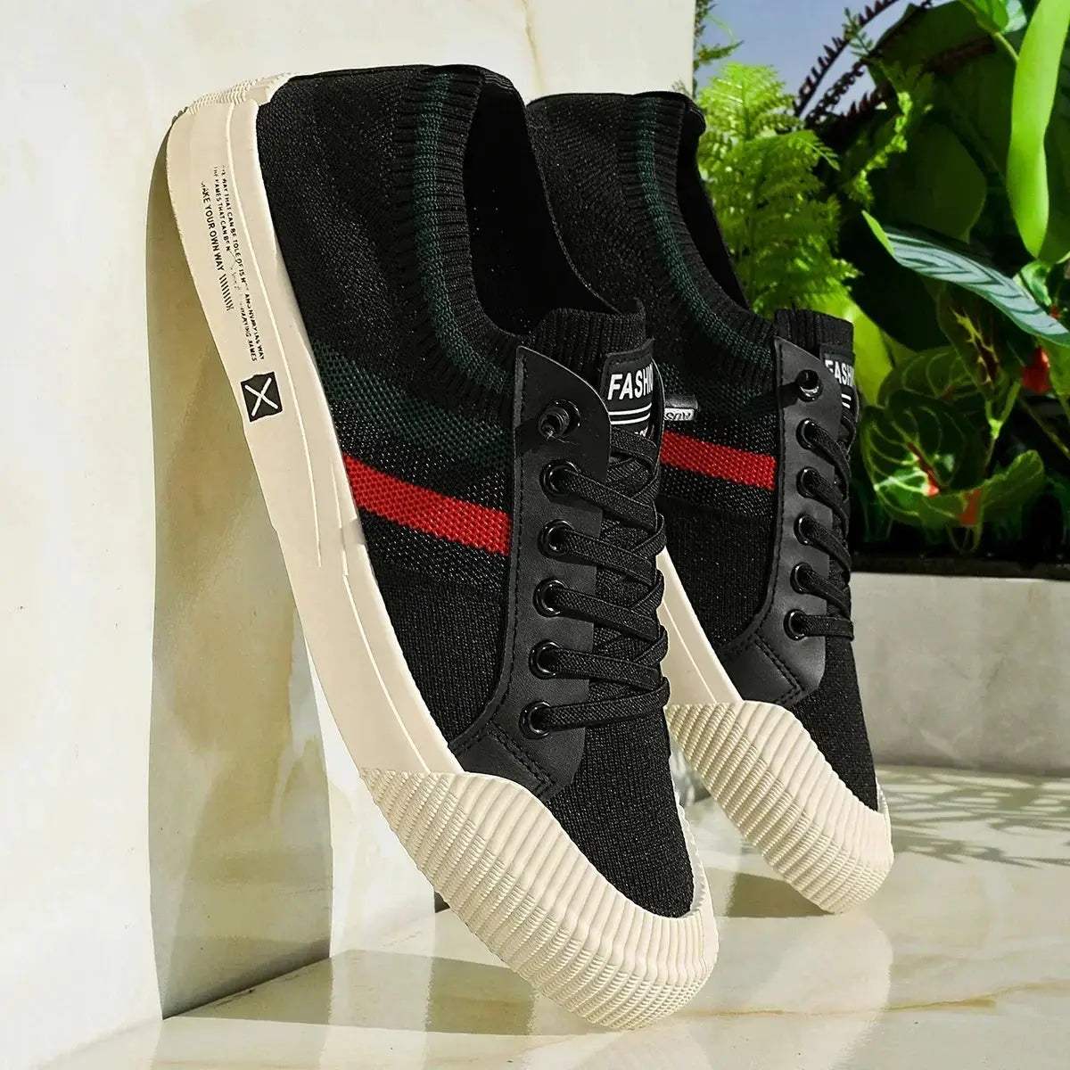 Pair of men's black knit sneakers with a red stripe, black laces, and cream soles