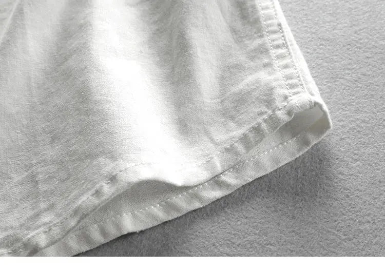 Men's white linen-cotton shirt close-up of hem, showcasing fabric texture and neat stitching.