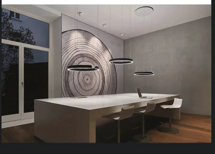 Three black ring ceiling chandeliers by Simples Market with LED lighting over a white dining table