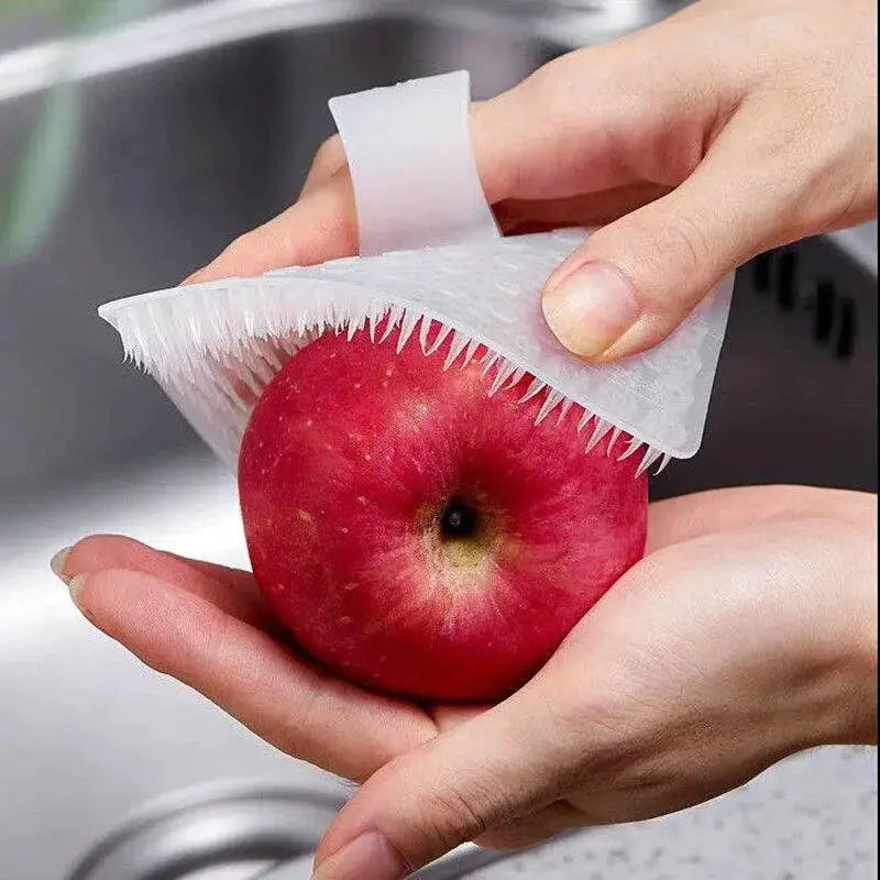 Simples Market silicone dish scrubber with bristle edge used to clean a red apple