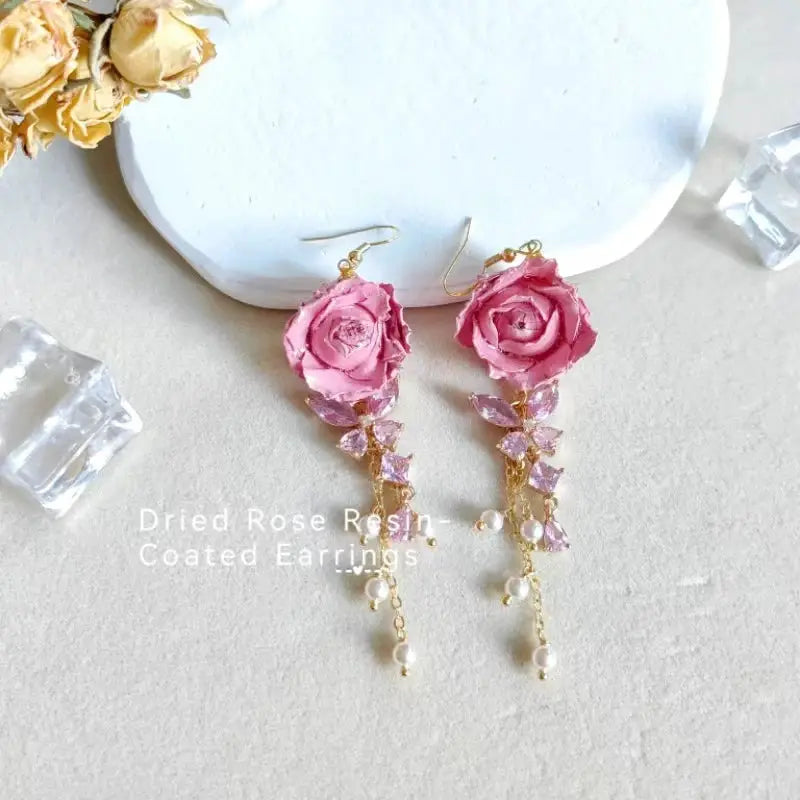 Elegant Immortal Rose long earrings pair with pink epoxy resin petals, gold-tone dangling chain, crystals and pearls