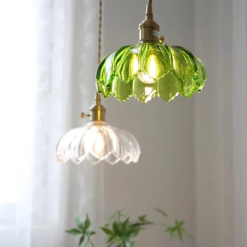 Set of two glass pendant lights with green and clear scalloped shades and brass fixtures, vintage style.