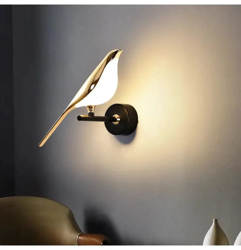 Magpie bird LED wall lamp in gold metal finish with a black wall mount.
