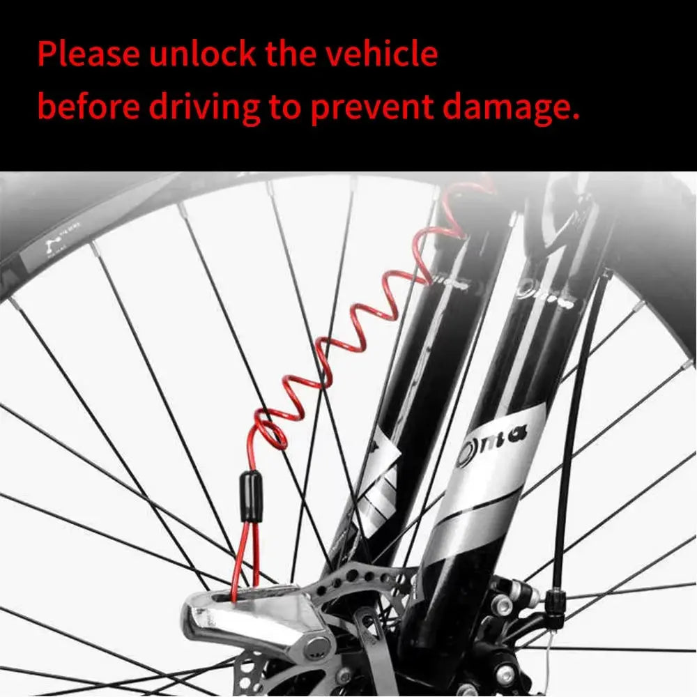 Red coiled reminder cable lock on the bicycle front fork beside the disc brake