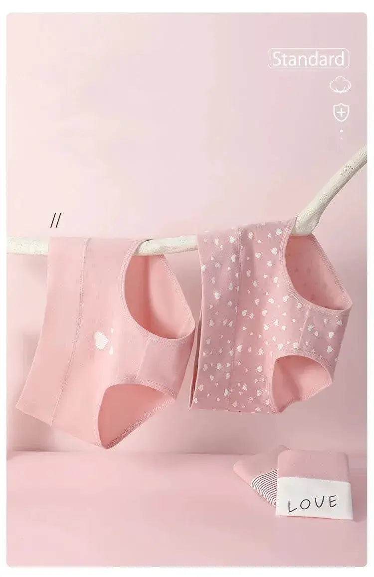 Two pink high-waist cotton panties, one solid pink and one pink with white hearts, hanging on a clothesline.