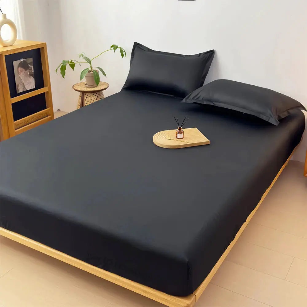 Simples Market waterproof fitted mattress cover on a dark gray sheet with matching gray pillows on a wooden bed.