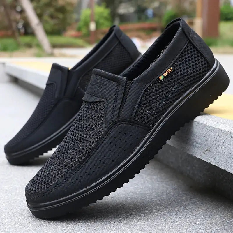 Men's slip-on casual shoes by Simples Market, black breathable mesh pair with rubber sole.