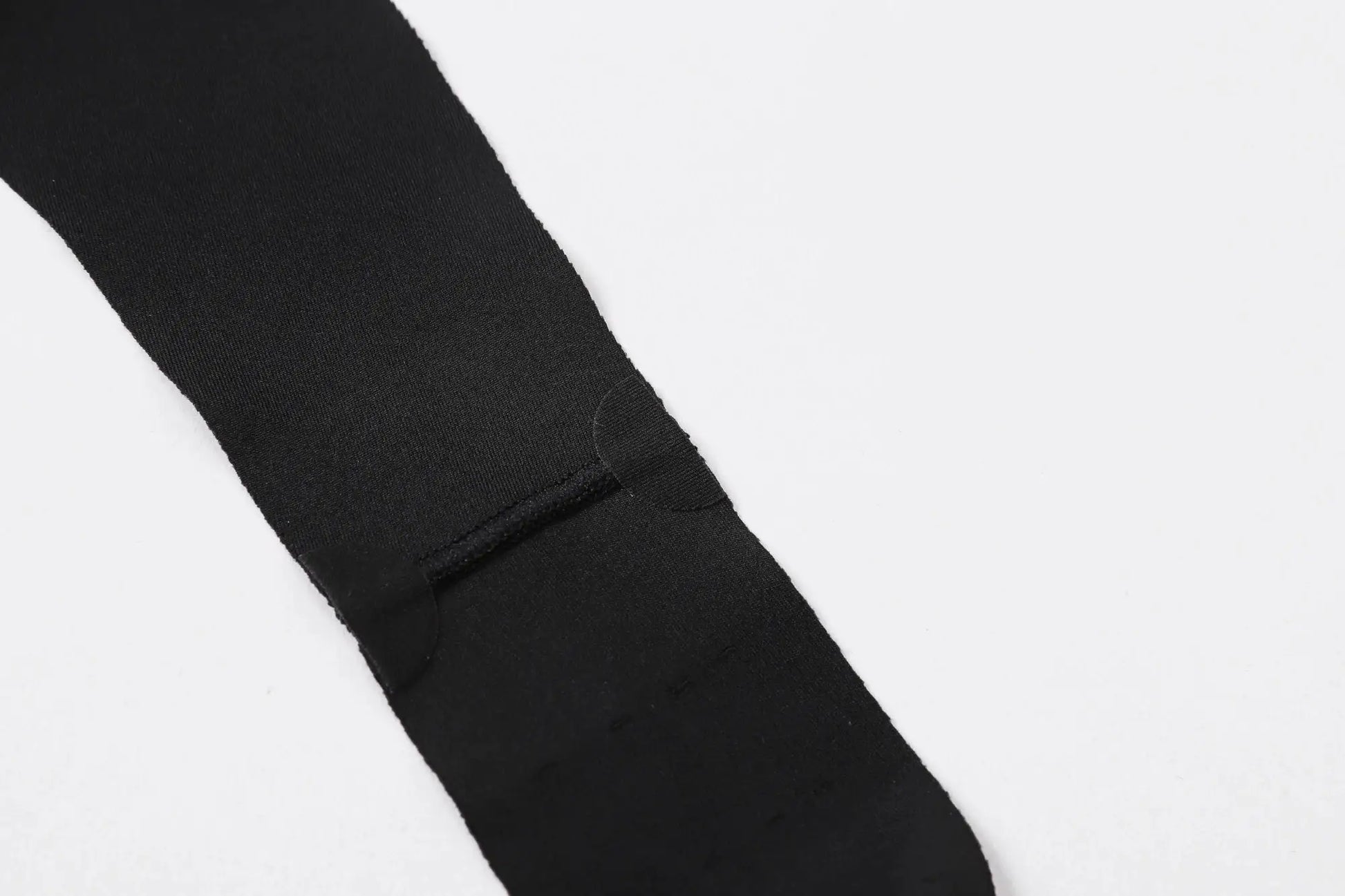 Black men's cycling bib shorts strap close-up, showing stretchy fabric and reinforced seam