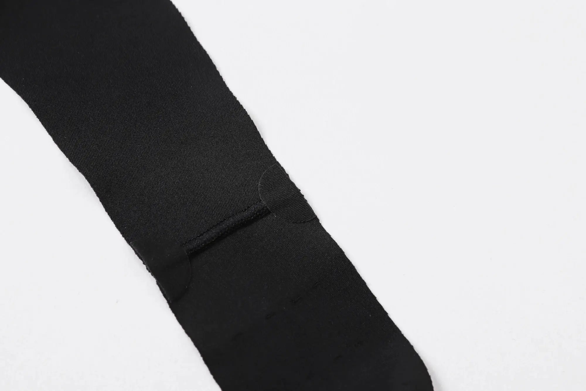 Black men's cycling bib shorts strap close-up, showing stretchy fabric and reinforced seam